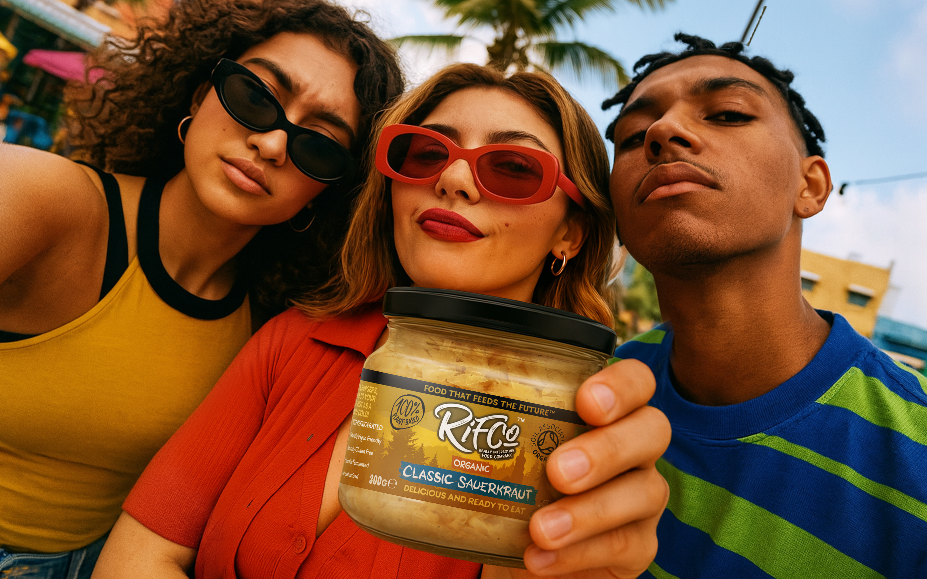 Three Gen-Z's holding RIFCo Classic Sauerkraut jar, promoting organic vegan fermented food in lifestyle street photography setting