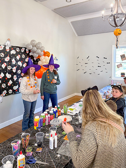 Two people assisting with arts and crafts at the Halloween party