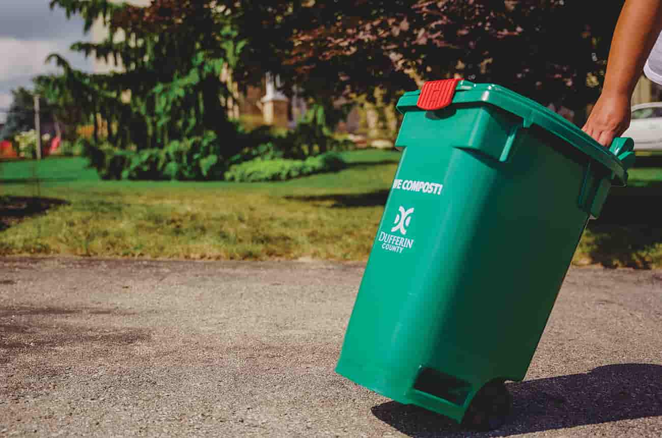 A person wheeling a Dufferin County Compost Bin