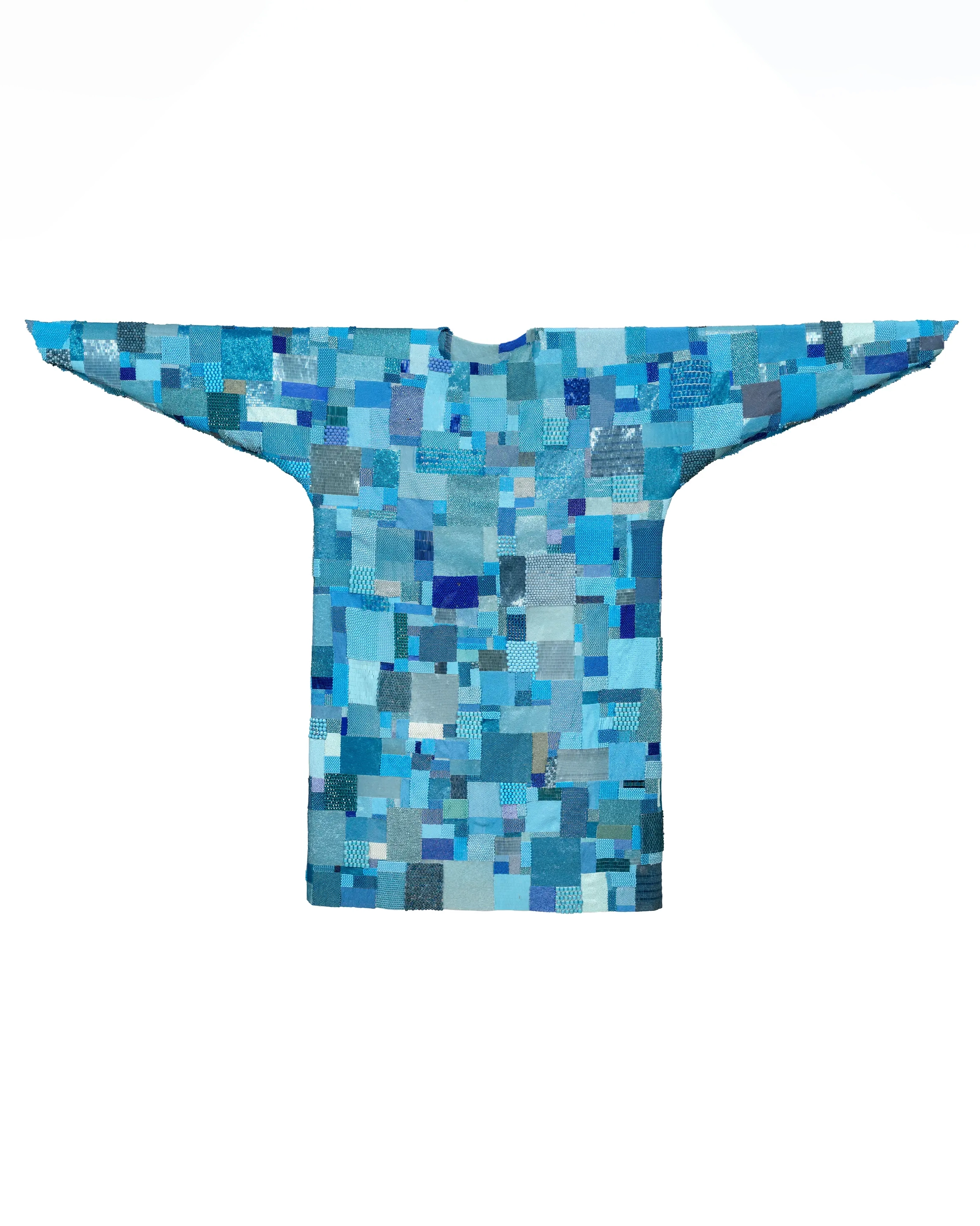 A patchwork hospital gown composed of small rectangular beaded swatches in varied shades of turquoise and blue, by artist Maggie Thompson.