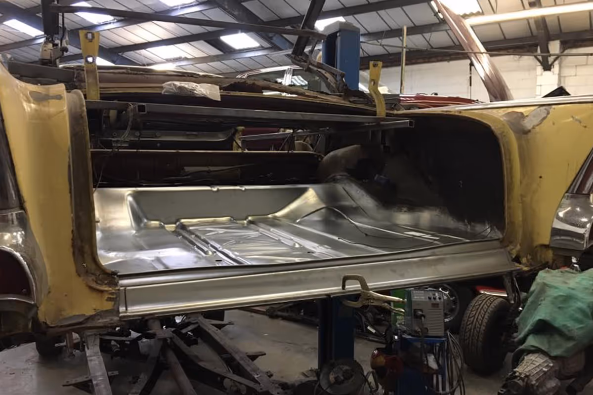 The rear section of a car is being repaired in a workshop garage.