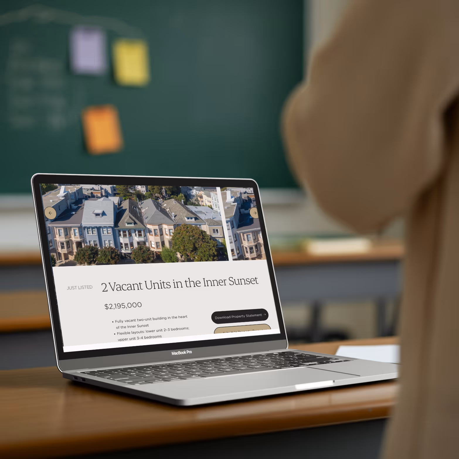 MacBook Pro displaying a real estate listing for 2 vacant units in the Inner Sunset priced at $2,195,000 on a wooden desk in a classroom.