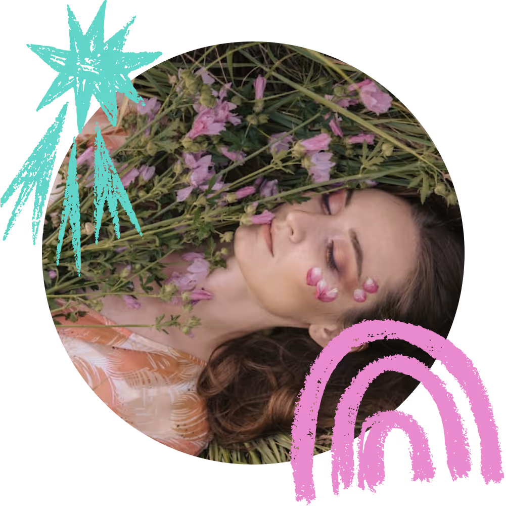 התמונה מציגה אישה שוכבת בעשב ובין פרחים סגולים, עיניה עצומות ועל לחיה מודבקים עלי כותרת עדינים. סביב התמונה נוספו איורים צבעוניים – כוכב טורקיז וקשת ורודה – שמעניקים לה אווירה חלומית ואמנותית.