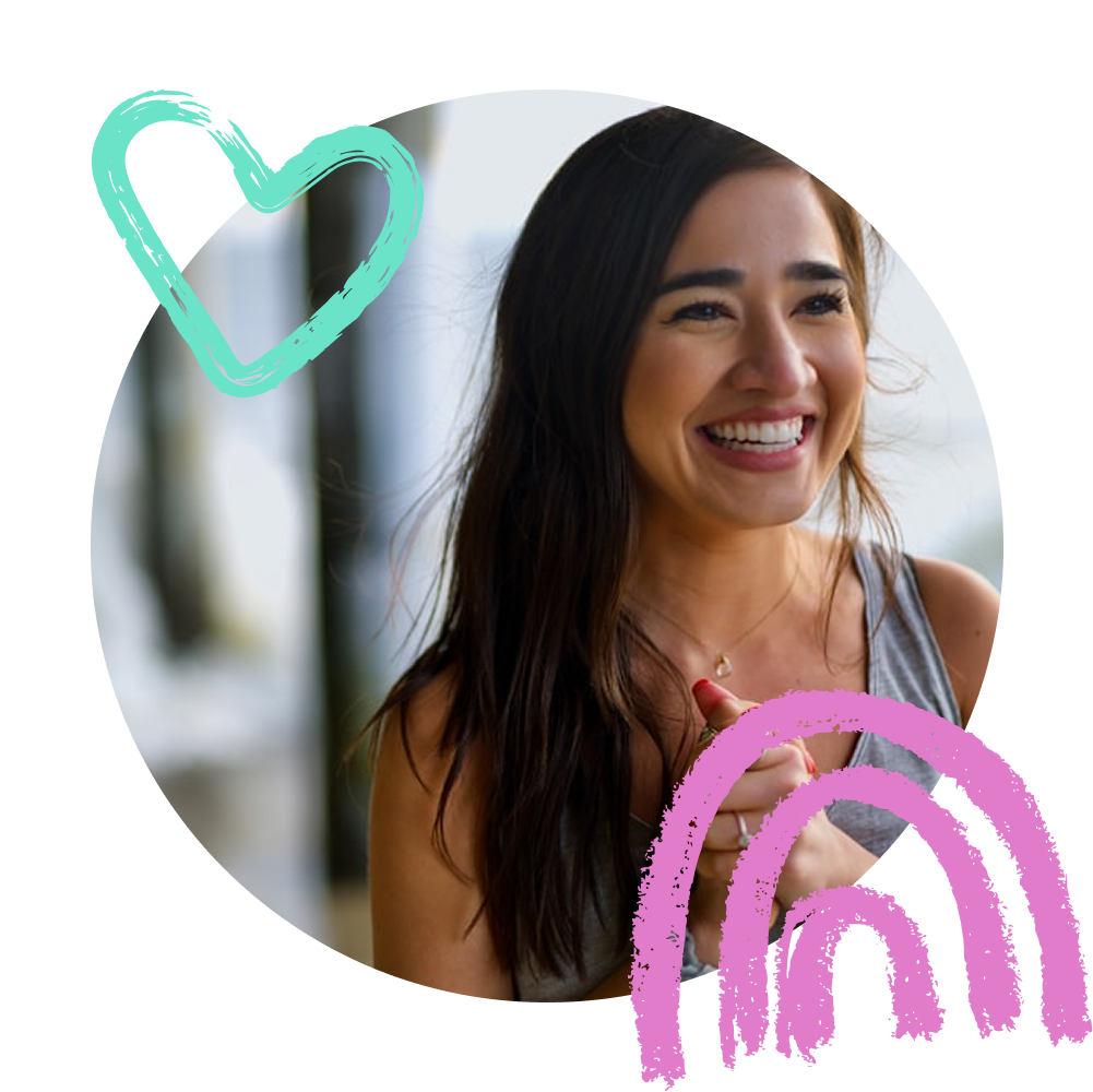 התמונה מציגה אישה מחייכת בשמחה, לבושה בגופייה אפורה עם שרשרת עדינה. שערה חום וארוך והיא מקרינה חיוניות ואנרגיה חיובית. סביב התמונה נוספו איורים צבעוניים – לב טורקיזי וקשת ורודה – המוסיפים תחושה קלילה ושובבה.