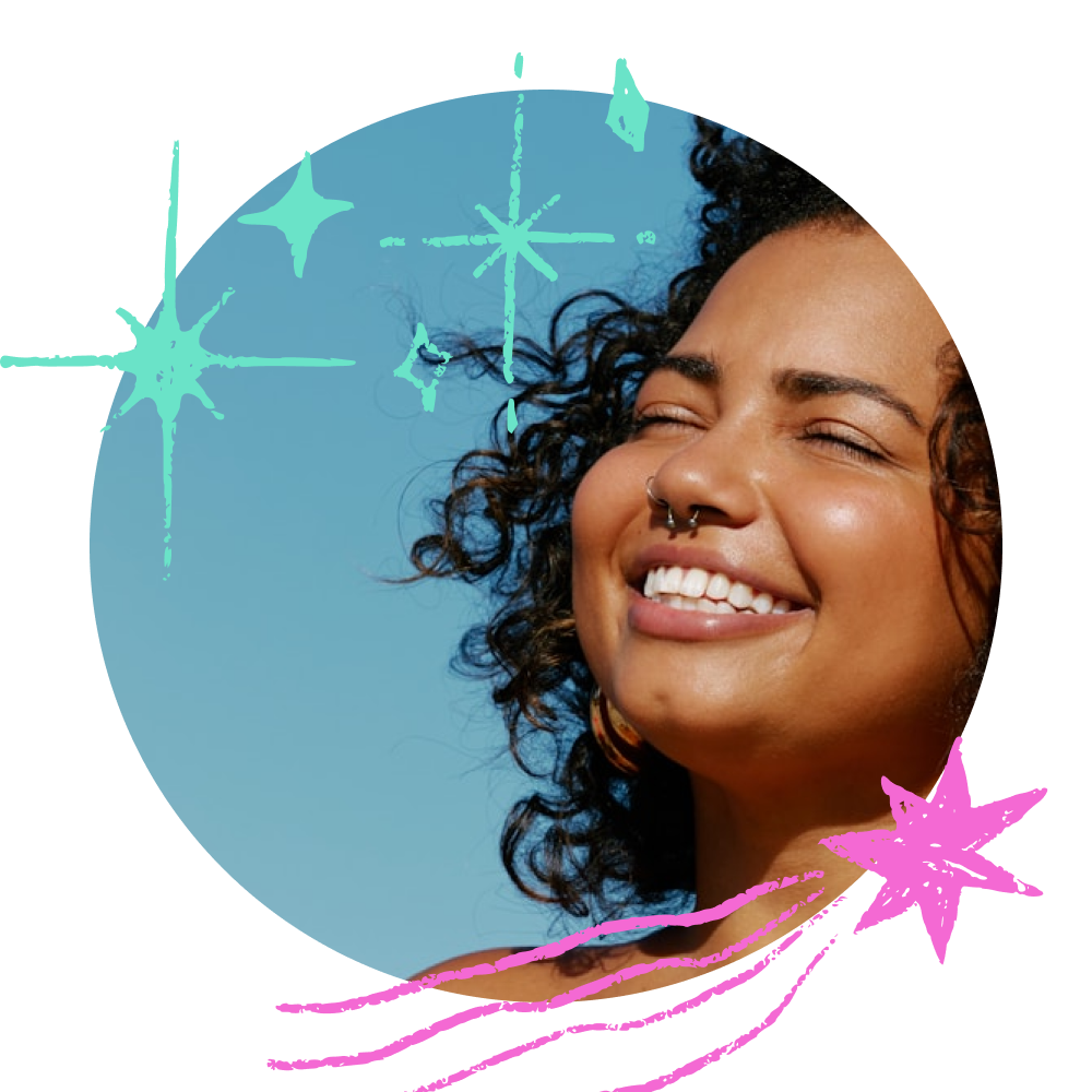 התמונה מציגה אישה שמחה עם שיער מתולתל ועגיל באף, מחייכת חיוך רחב תחת שמיים כחולים ובהירים. איורים שובביים של כוכבים בטורקיז וכוכב נופל ורוד מקיפים אותה, ומוסיפים לתמונה אווירה חלומית, מעצימה וחגיגית.