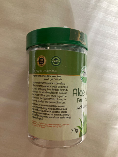Transparent jar with green lid containing Aloe Vera peel powder, showing label with usage instructions and benefits.