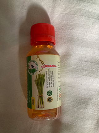 Small transparent bottle with red cap containing orange liquid, labeled with lemongrass image and text.