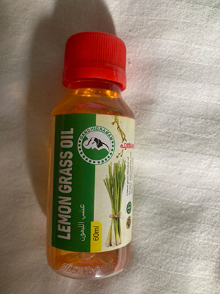 Small transparent bottle of lemon grass oil with a red cap and label featuring lemongrass stalks.