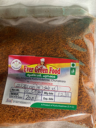 Clear plastic bag filled with brown spice powder labeled Ever Green Food from Anugraha Kudumbashree, Chunakkara with manufacturing and expiry dates.