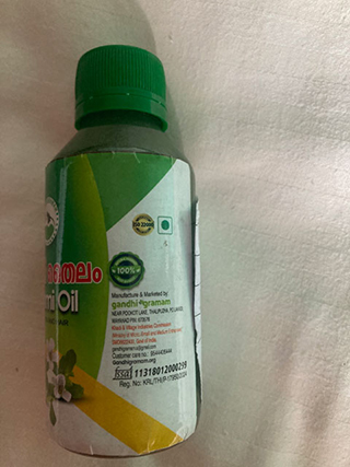 Small green-capped bottle labeled as sesame oil with partial text in Malayalam and English on the label.