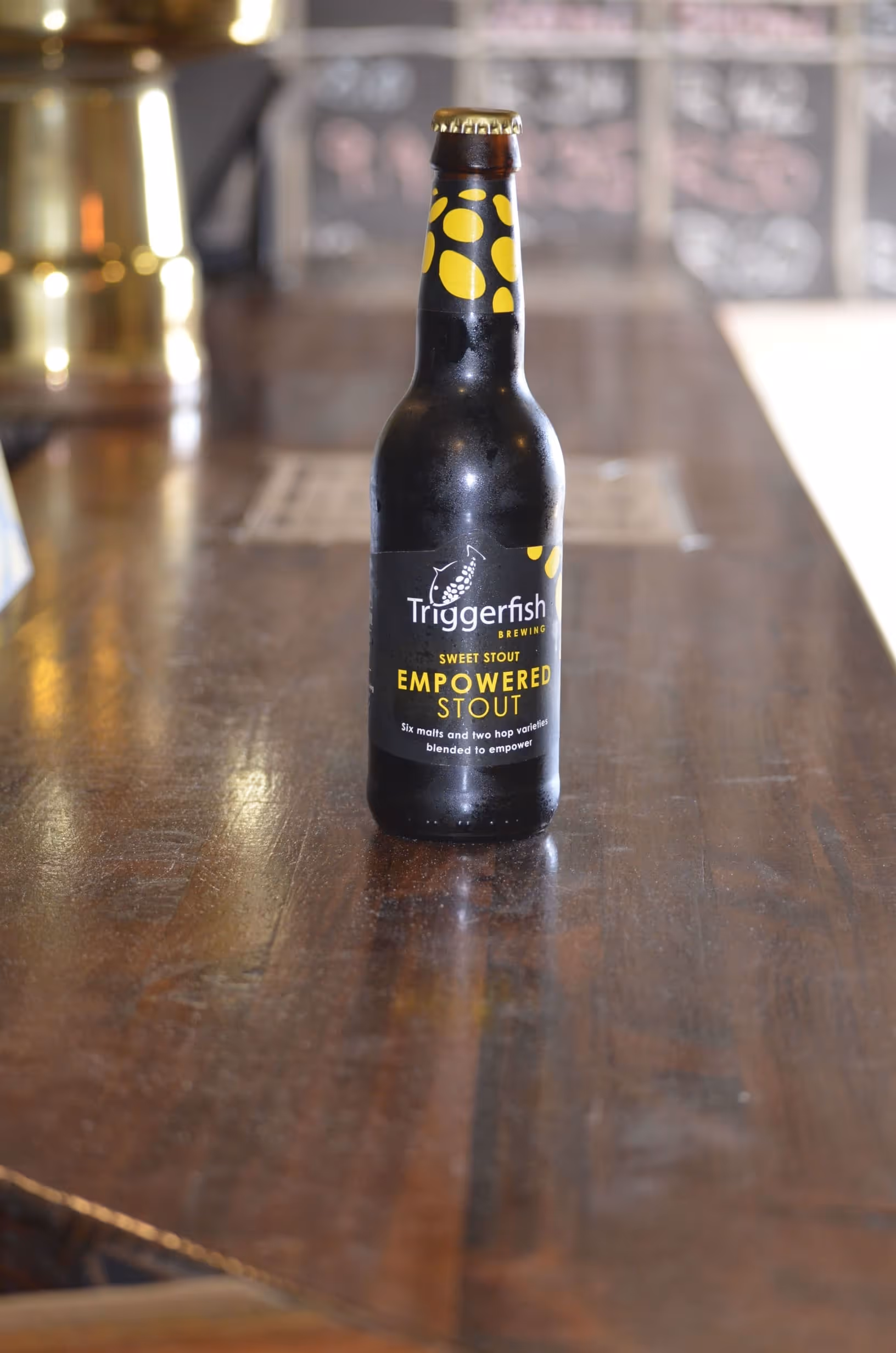 A closed bottle of Triggerfish beer on a wooden bar counter
