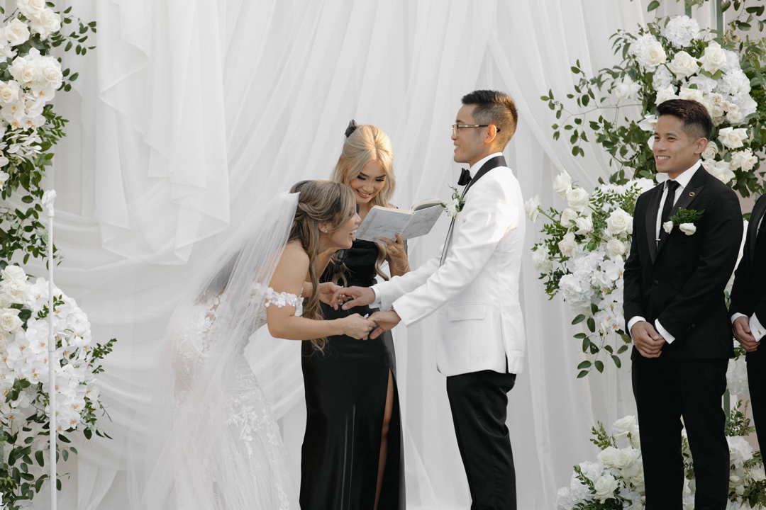 Bride and groom dressed i white exchange vows on stage at Hangar 21 South.
