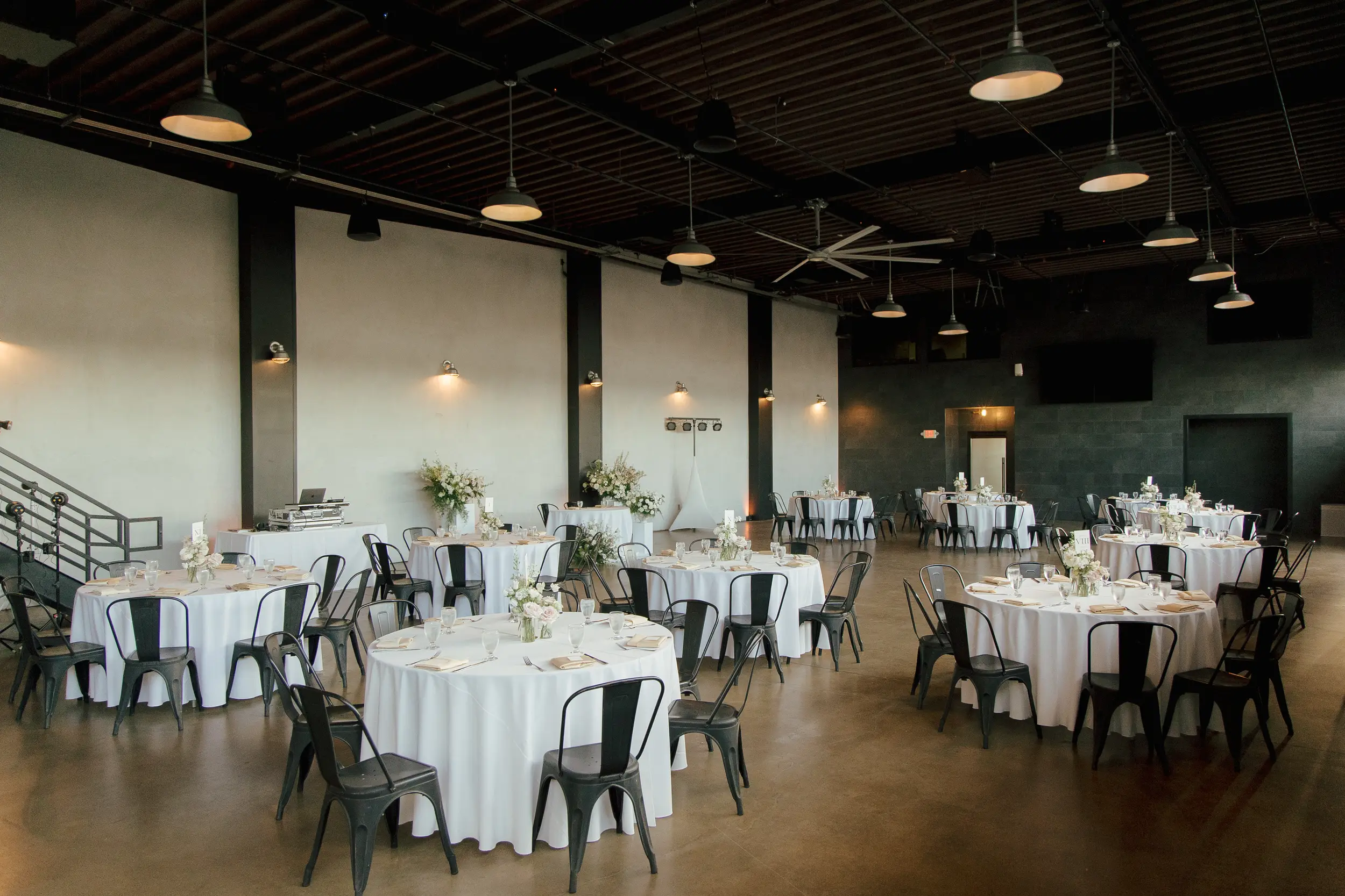 The reception is set with tables draped in white linens and topped with fresh floral centerpieces.