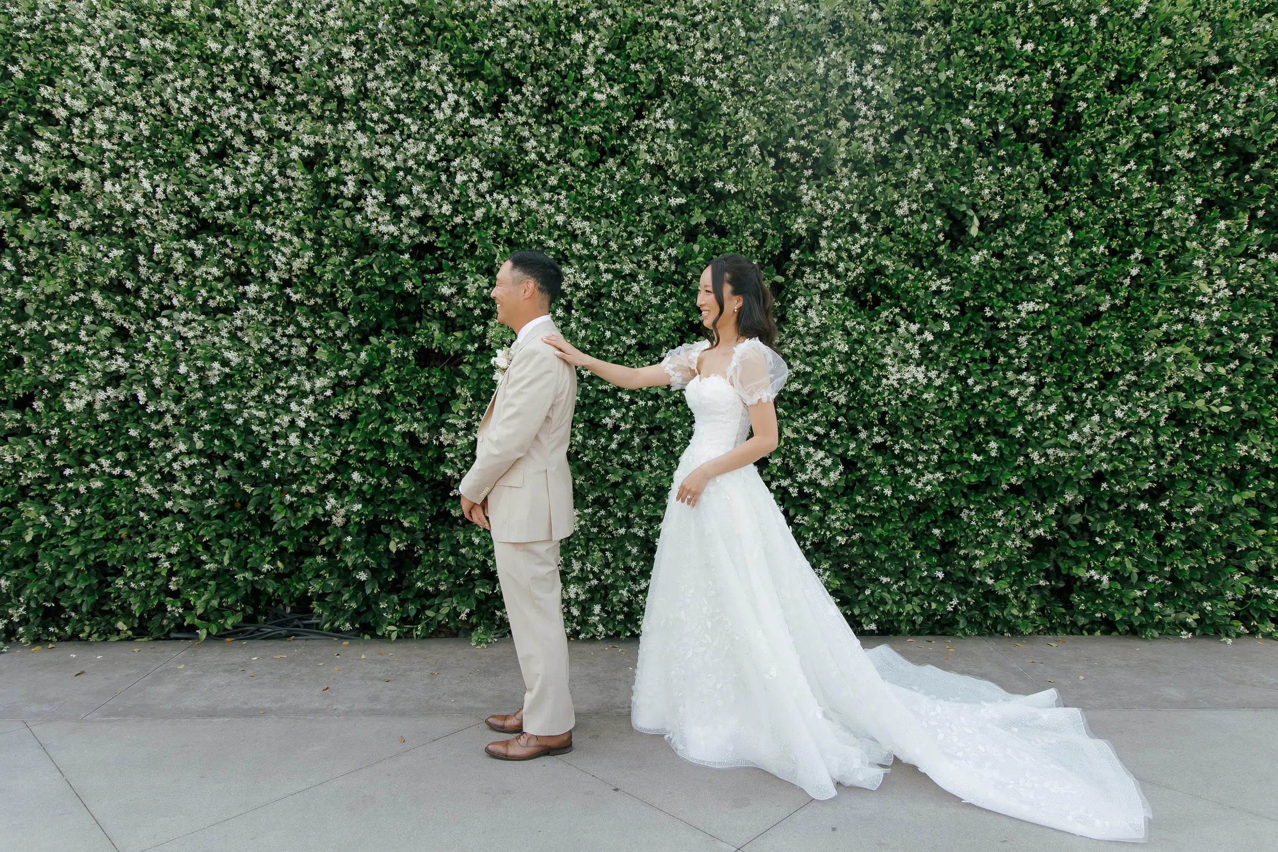 Bride and groom share first look in front of wall filled with jasmine flowers.