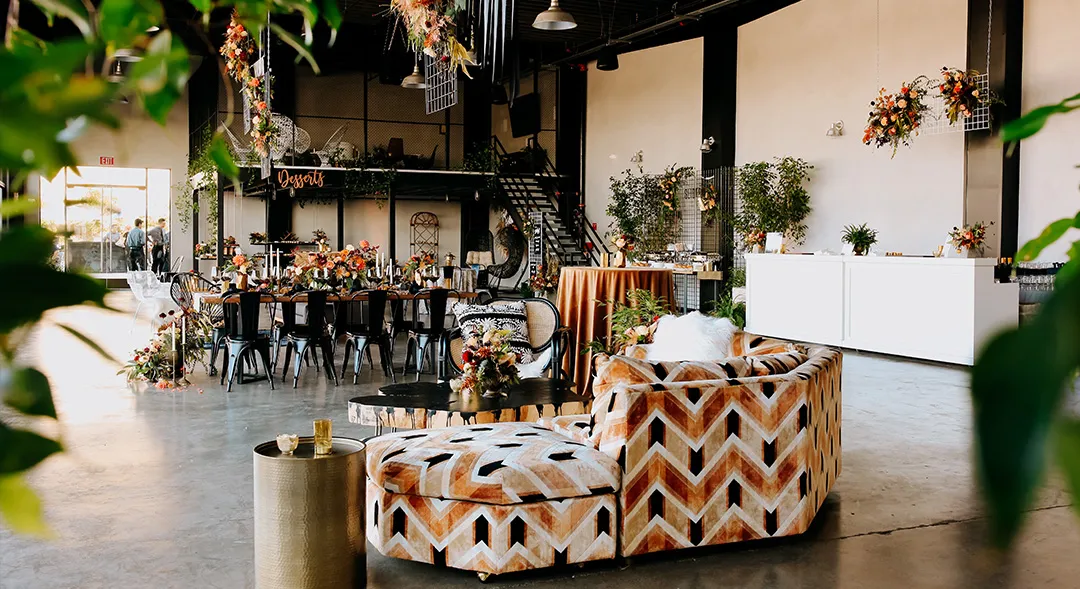 Patterned lounge seating, floral arrangements and reception tables inside Hangar 21
