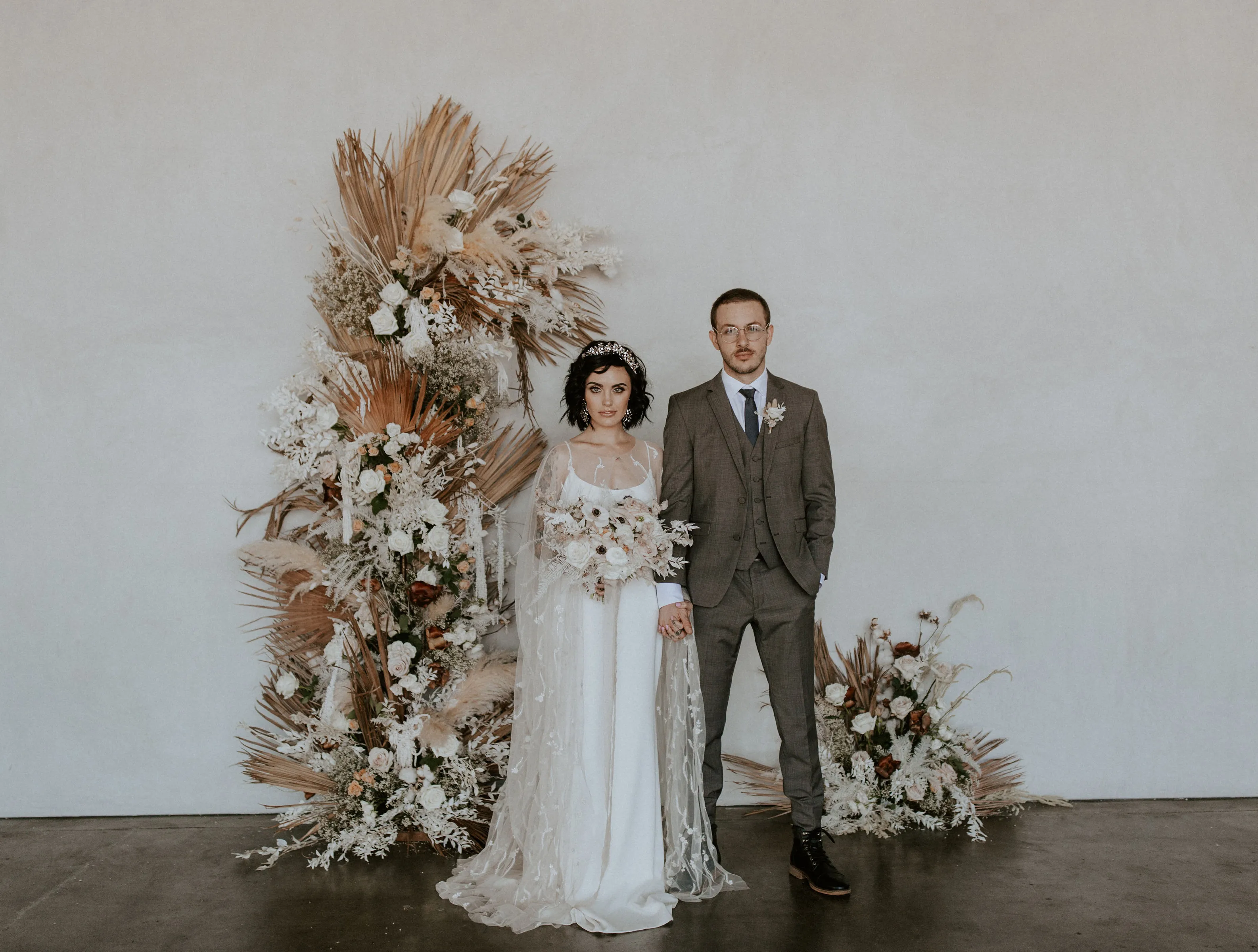 Wedding couple beside a floral ceremony arrangement