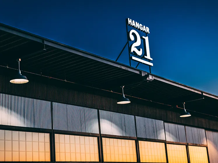 Illuminated Hangar 21 sign and hangar exterior at dusk