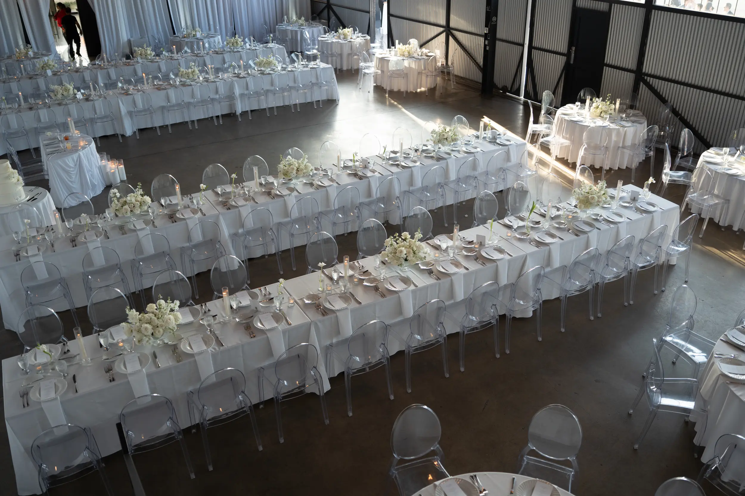 White drapery, floral arrangements and candlelit reception tables inside Hangar 21
