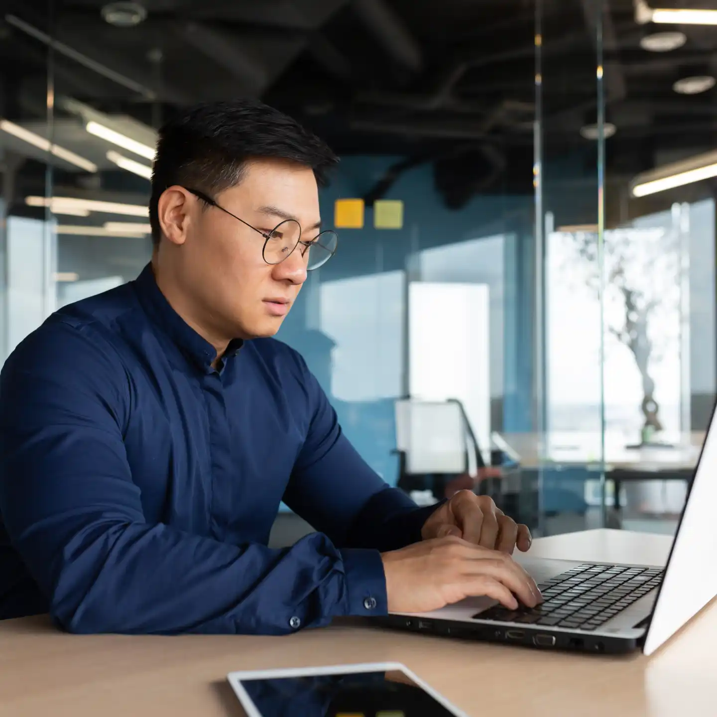 Man in an office at his desk working on a laptop computer