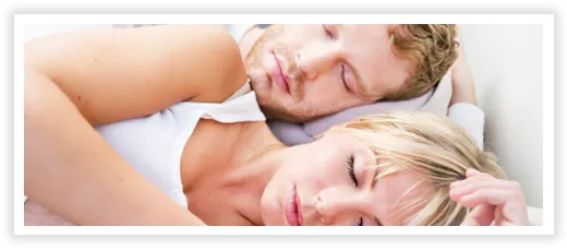 Couple peacefully sleeping together in bed with closed eyes.