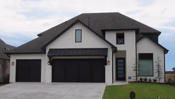 Two-story modern house with white exterior, dark roof, three-car garage with black doors, and a neatly trimmed green lawn.