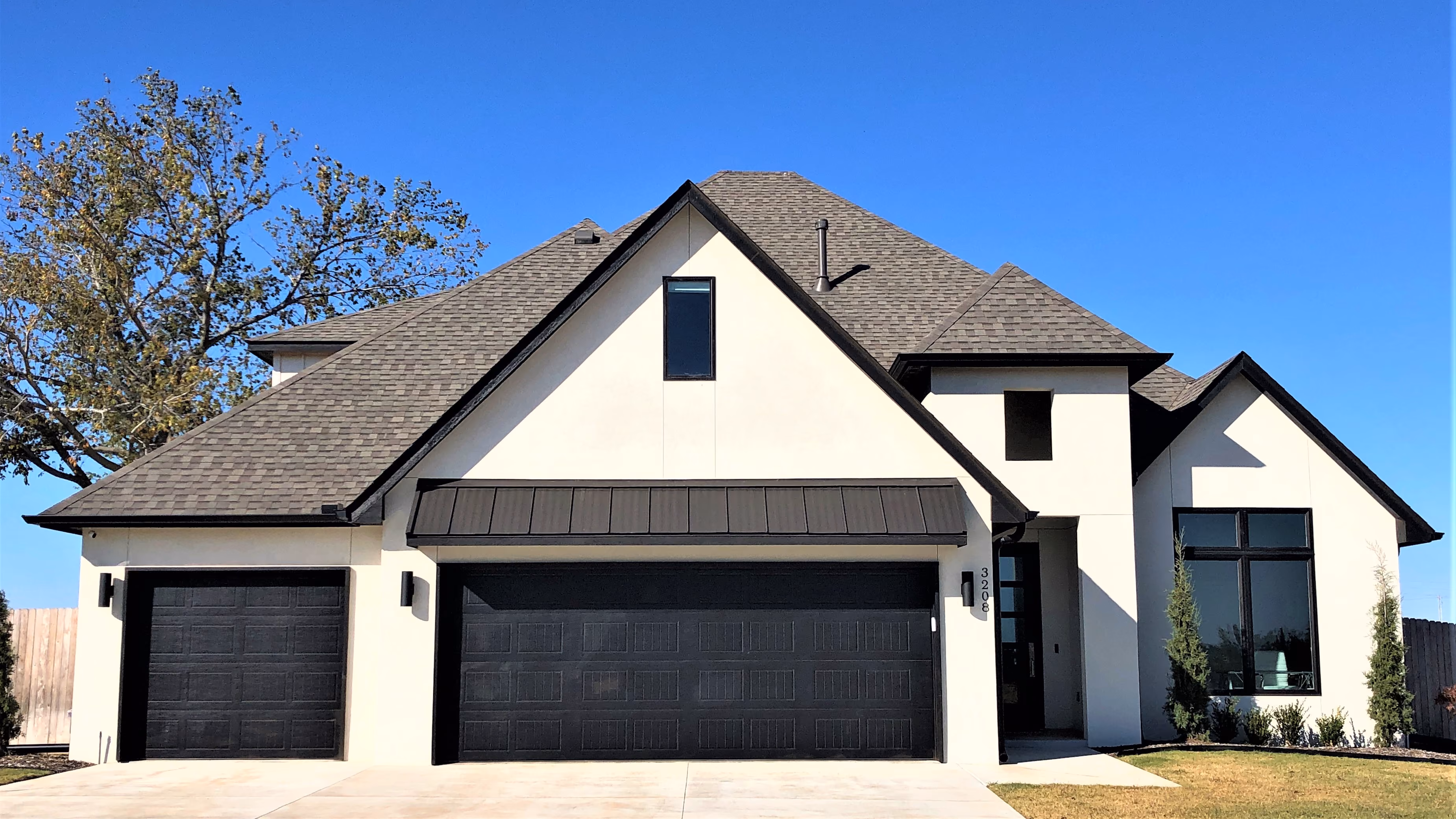 Modern two-story house with white exterior, dark trim, and a large double garage under a grey shingled roof.