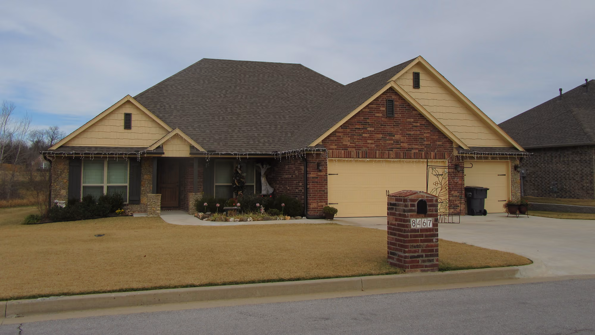 Single-story brick and stone suburban house with a large garage and brick mailbox with number 8467.