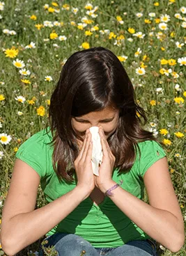 A young woman holding a towel up to her nose.