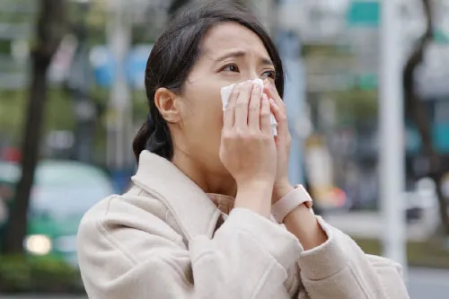 A woman with teary eyes holding a napkin to her face.