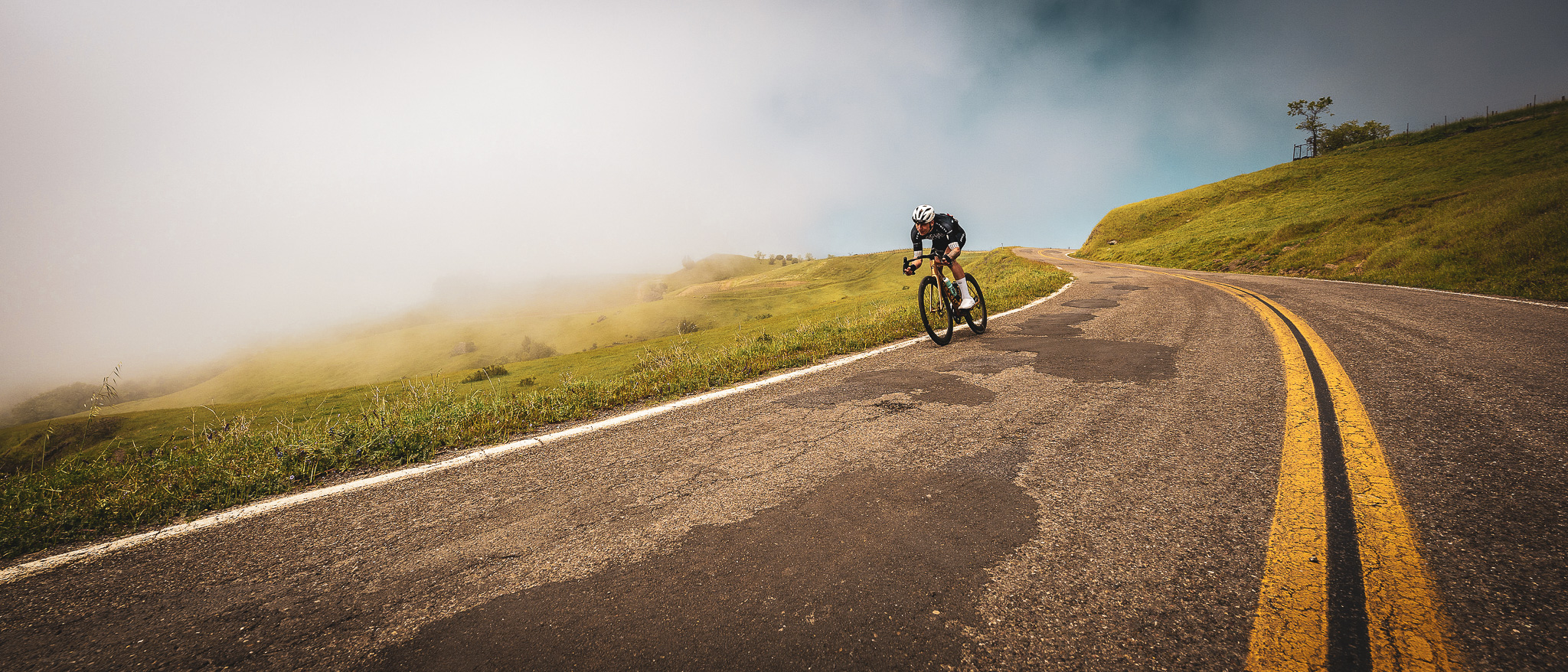 A cyclist descending a foggy ridge road in Sonoma County