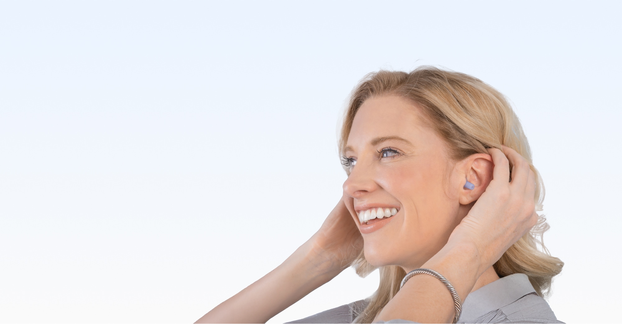 Picture of a model smiling with EarPlanes earplugs in her ears.