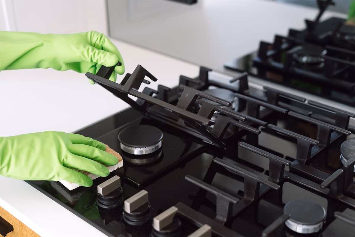 A cleaning technician is cleaning a stovetop.