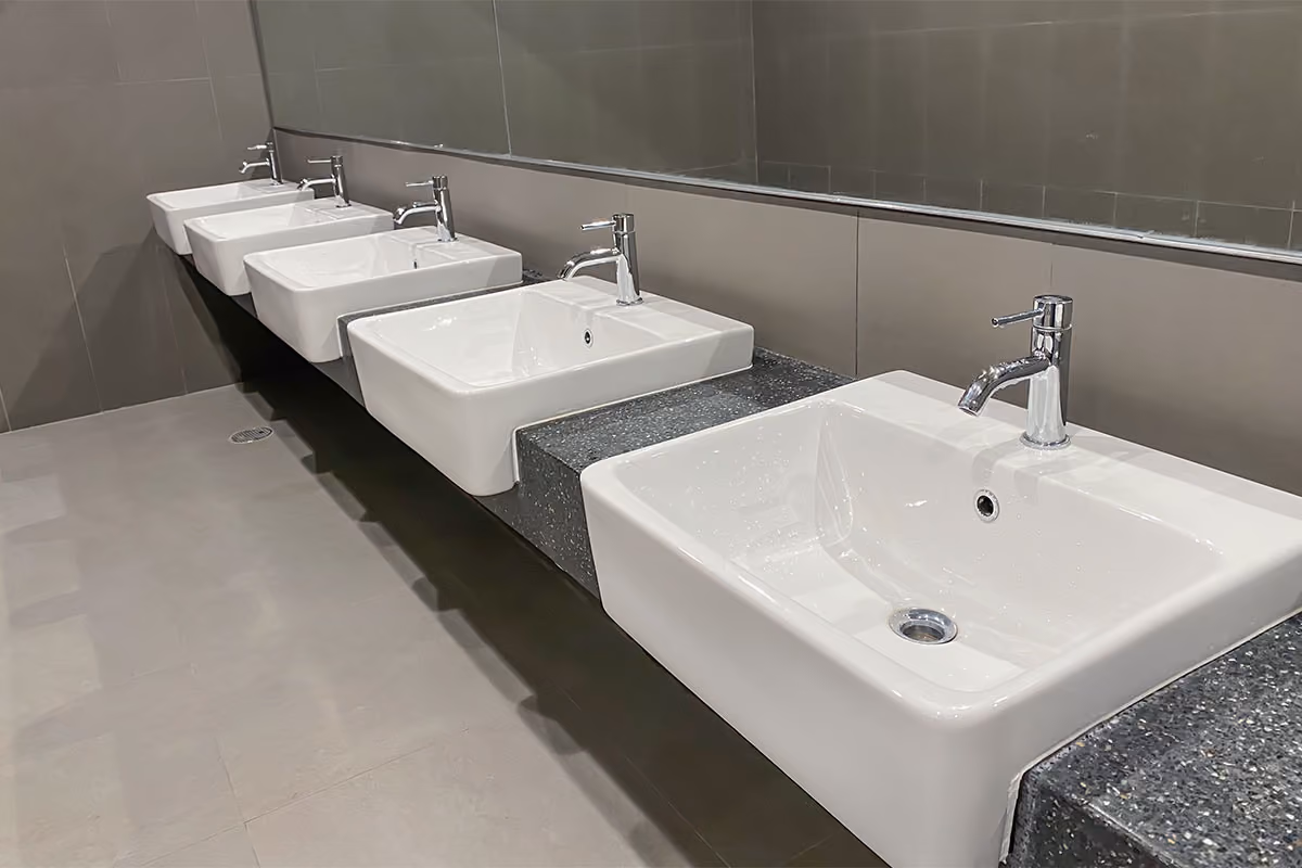 A row of clean sinks in a public washroom in an office building.