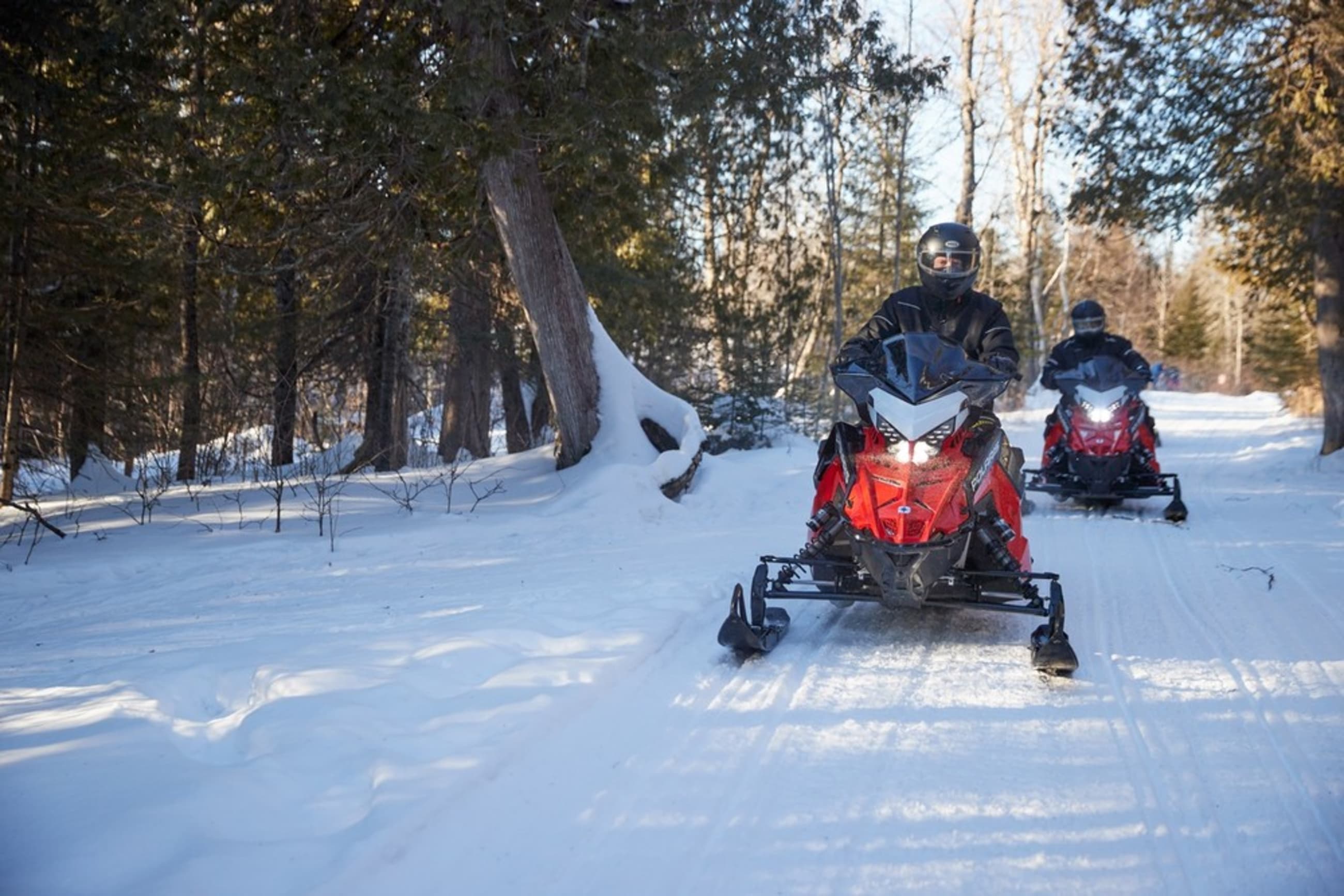 Snowmobilers riding on a snowy mountain trail