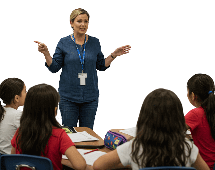 Primary school teacher explaining learning concepts to small group of pupils in classroom