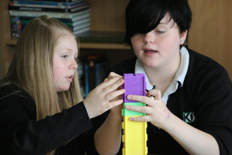 Students collaborating with digital tools and environmental resources in a modern classroom setting