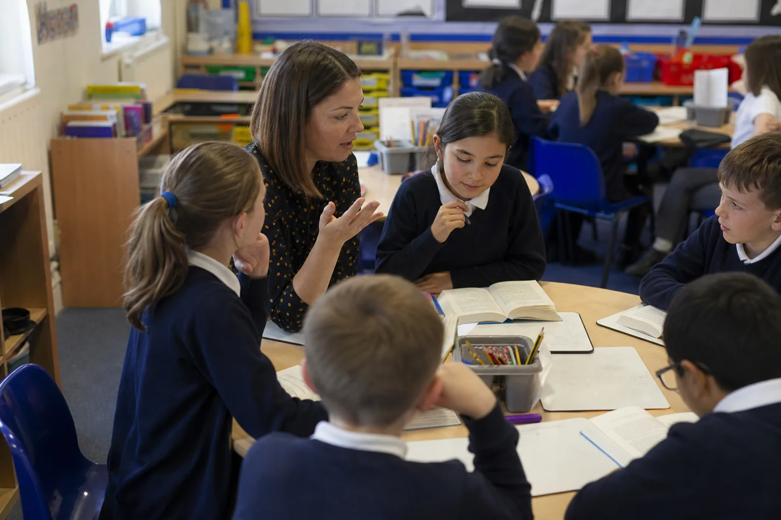 Teacher and learners use guided reading and comprehension prompts together in a UK classroom.