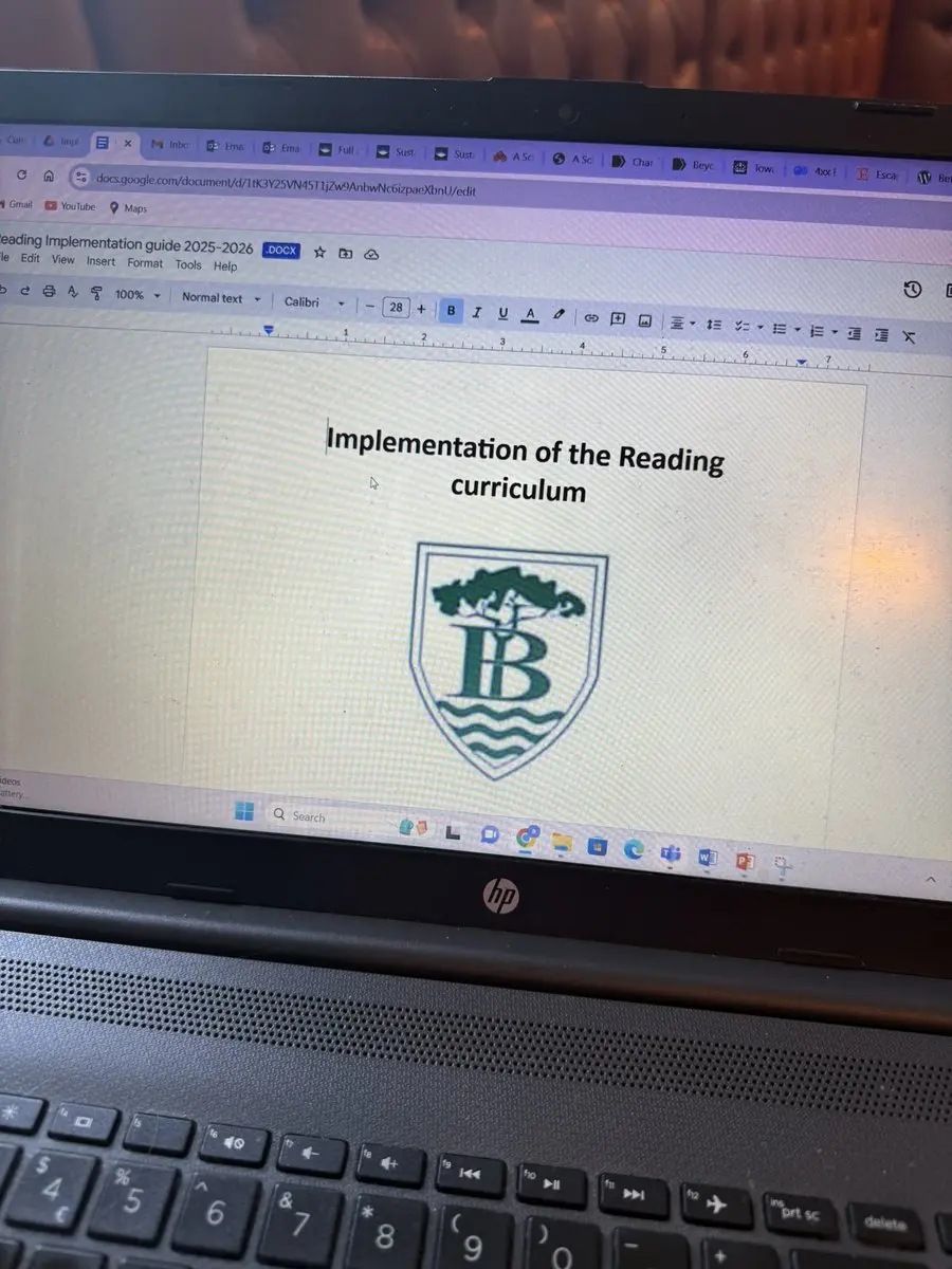 A laptop displaying the cover of a reading-curriculum implementation document in the original post.