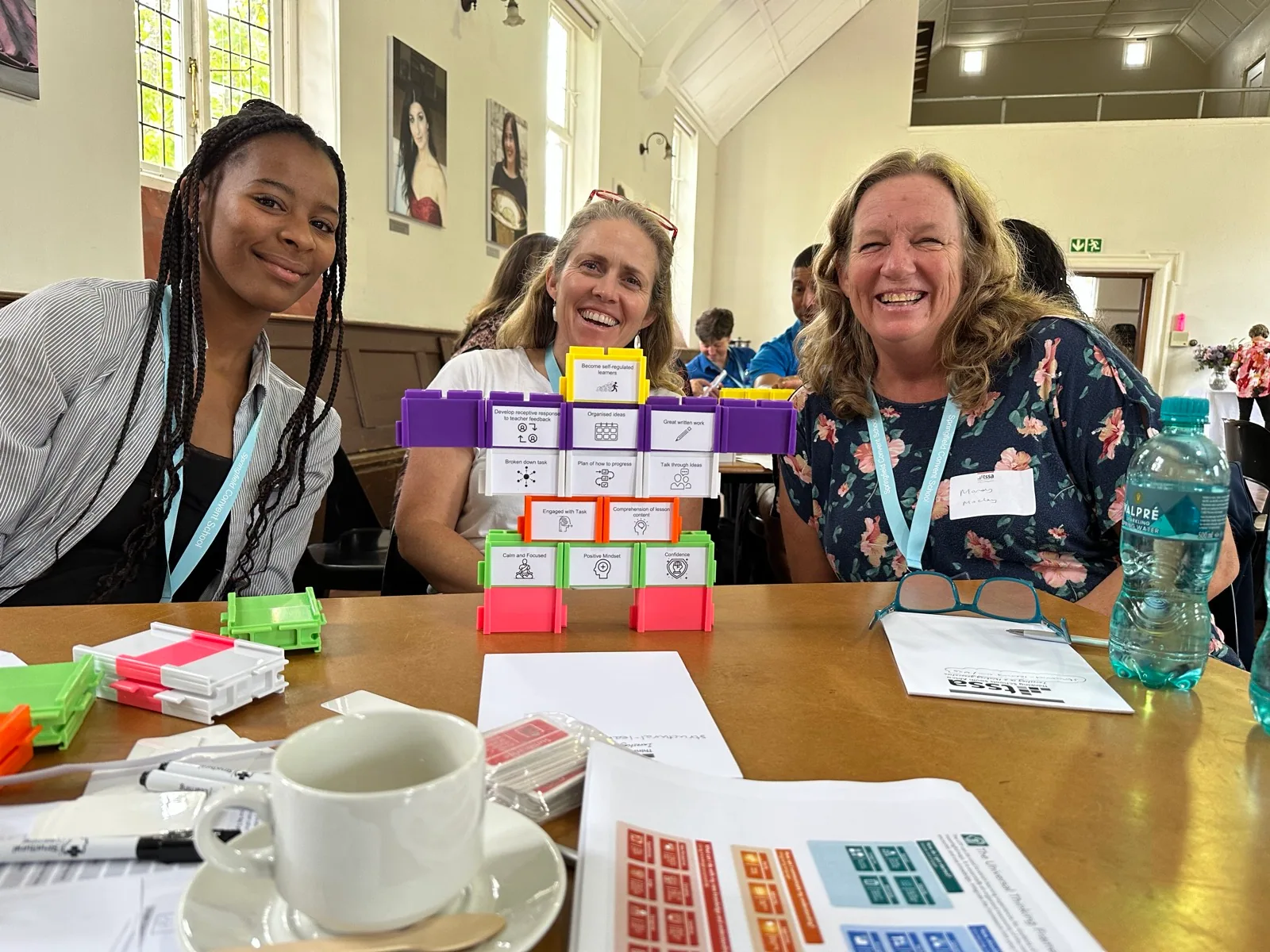 Three teachers smiling behind a wall of labelled Writer's Block, at a session in Cape Town.
