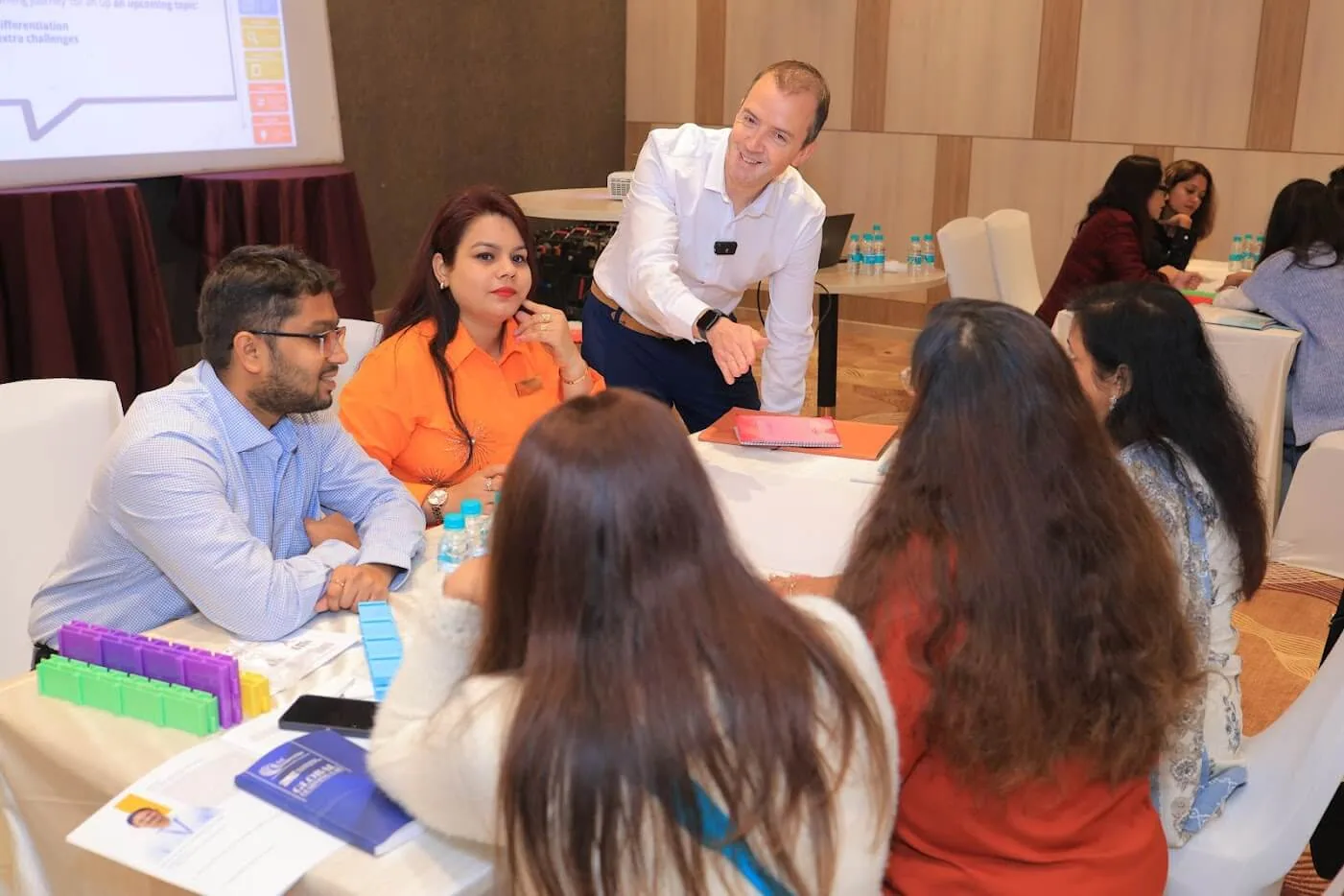Paul Main leaning over a table of teachers in Delhi as they build with Writer's Block