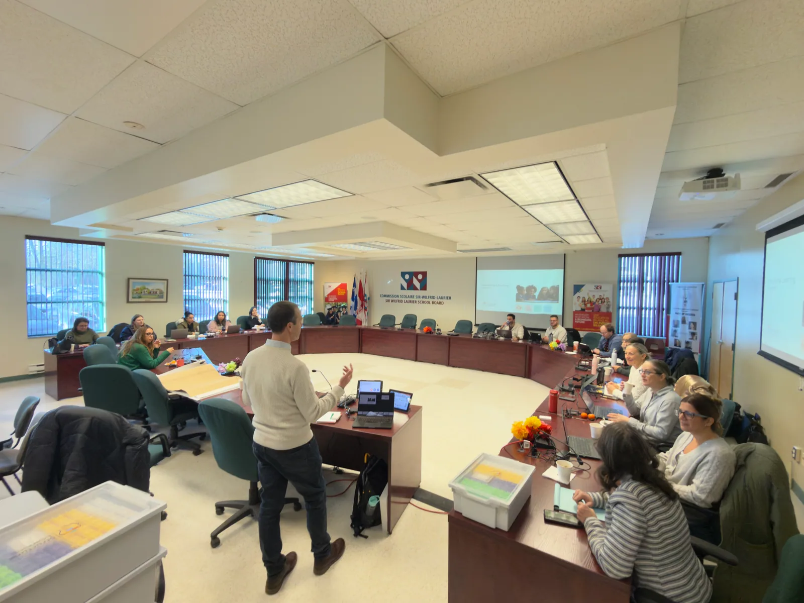 Paul Main presenting to teachers and leaders seated round the board table of the Sir Wilfrid Laurier School Board in Quebec