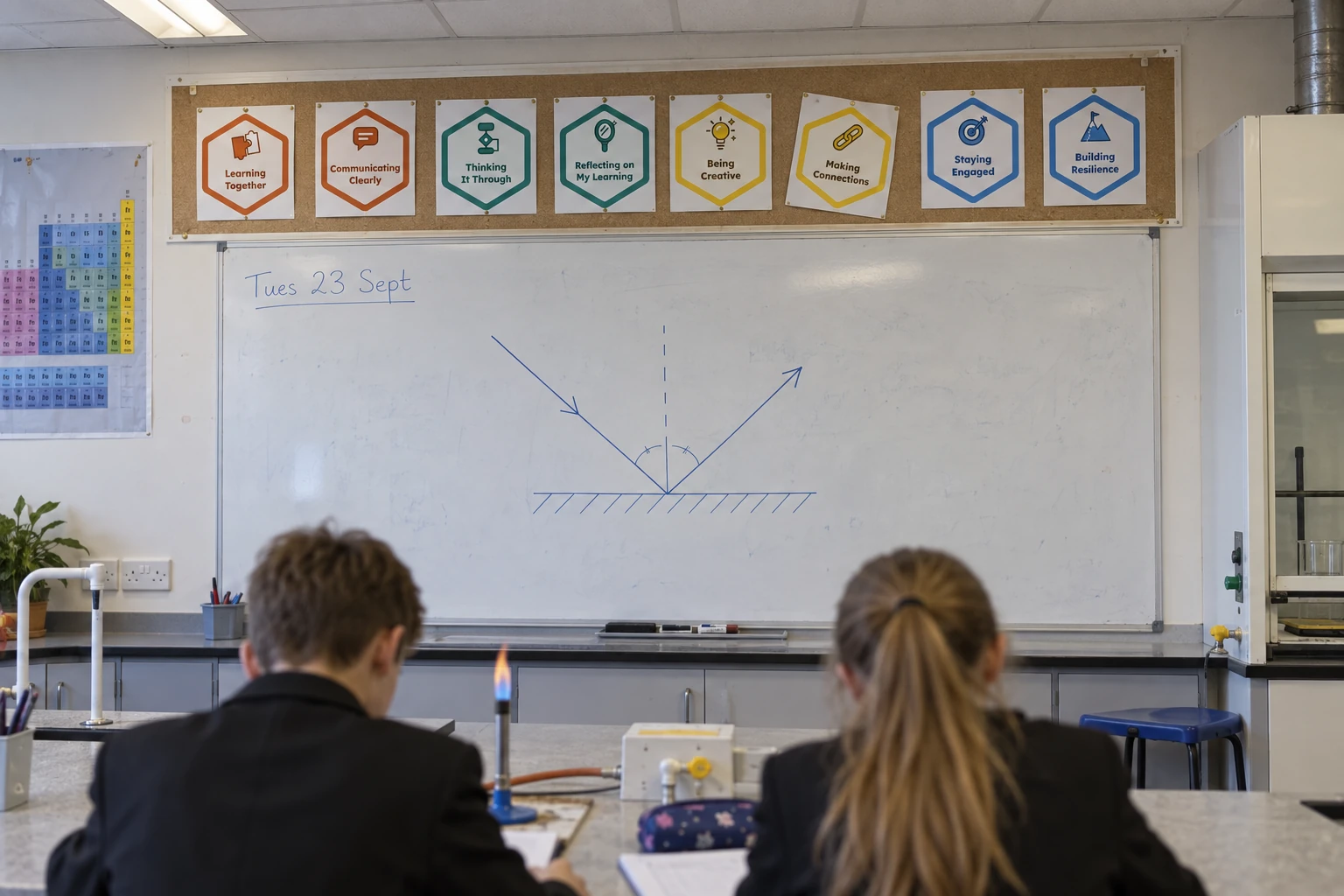Illustration of a science laboratory for learners aged 12 to 13, with the eight hexagon badges in one row on a cork strip above a whiteboard showing a diagram of light reflecting off a mirror.
