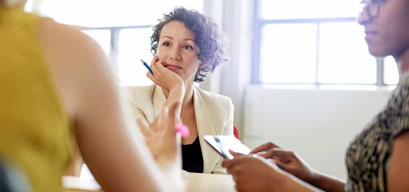 3 women sitting at desk talking to each other