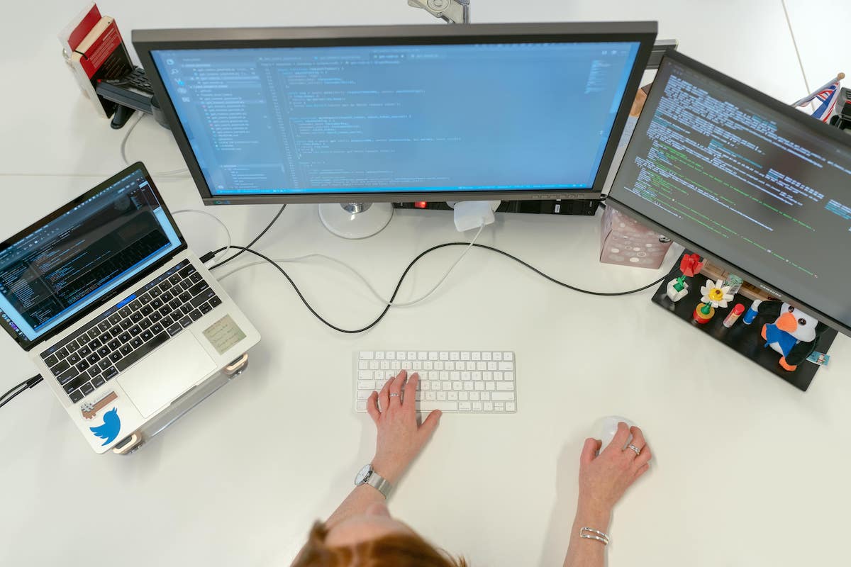 A person working at their desk with multiple monitors