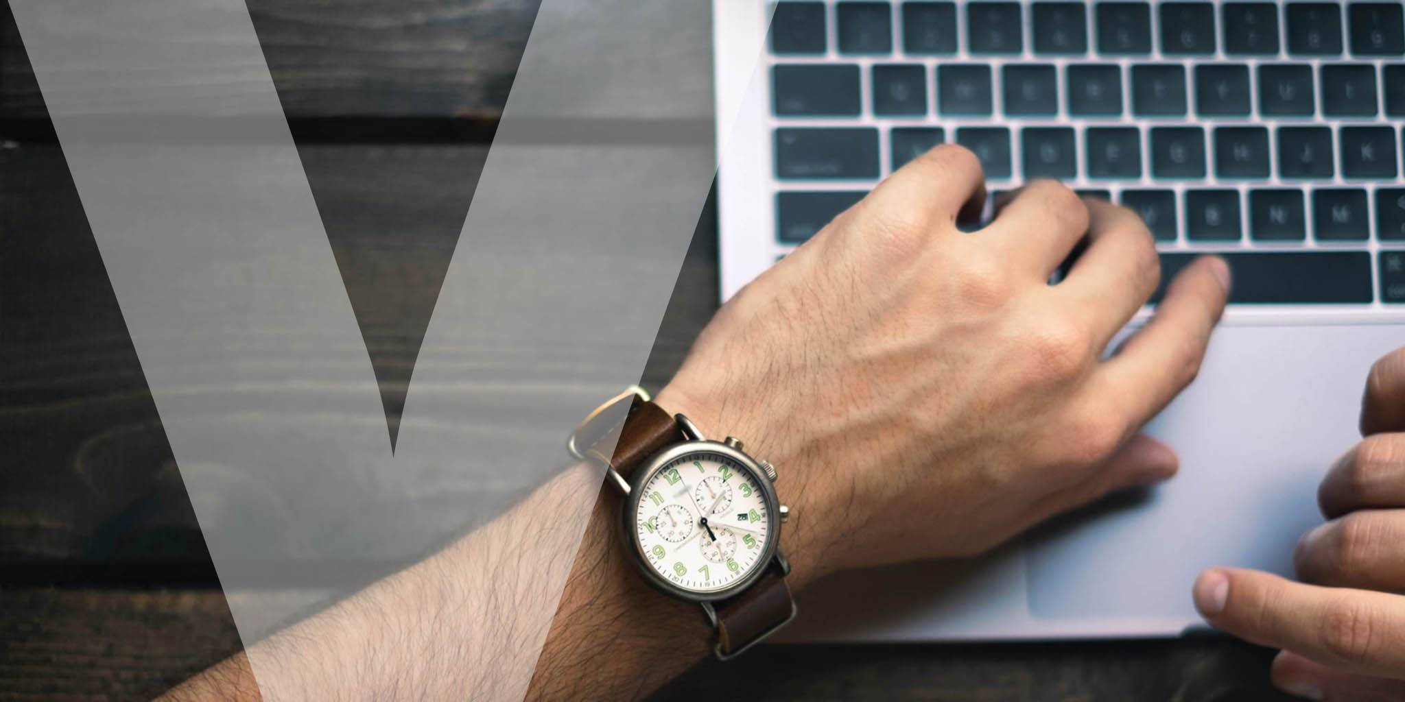 A hand with a wrist watch resting on a laptop