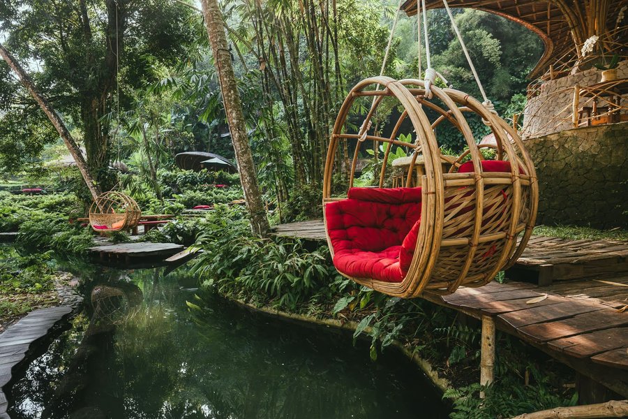 Altalena di bambù sulla piscina d’acqua di sorgente del Bambu Indah, nella foresta di Sayan, a Bali