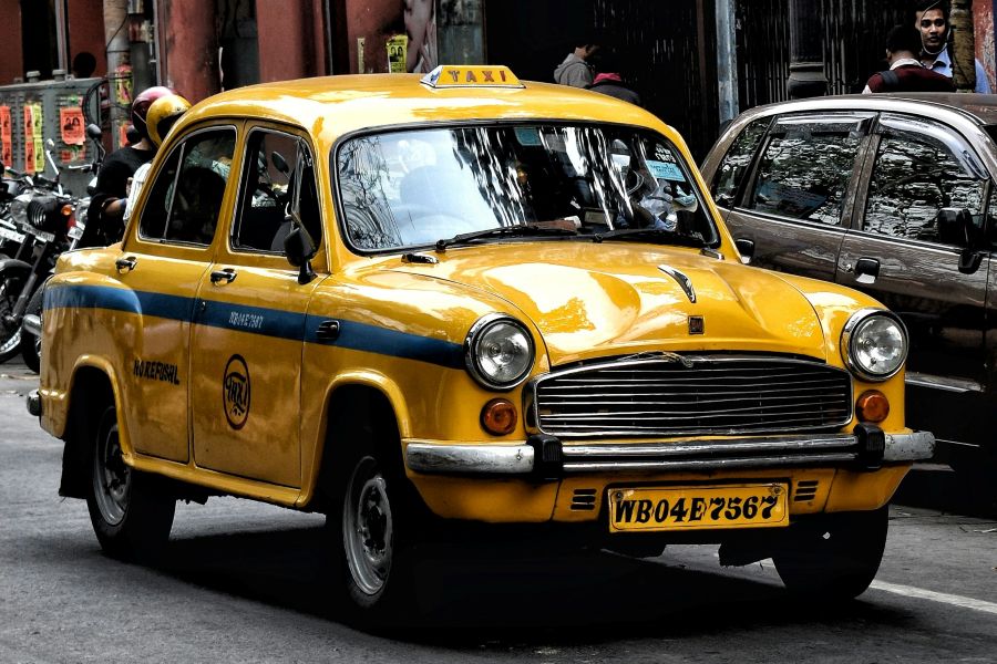 Yellow and blue classic Indian taxi cab on a city street.