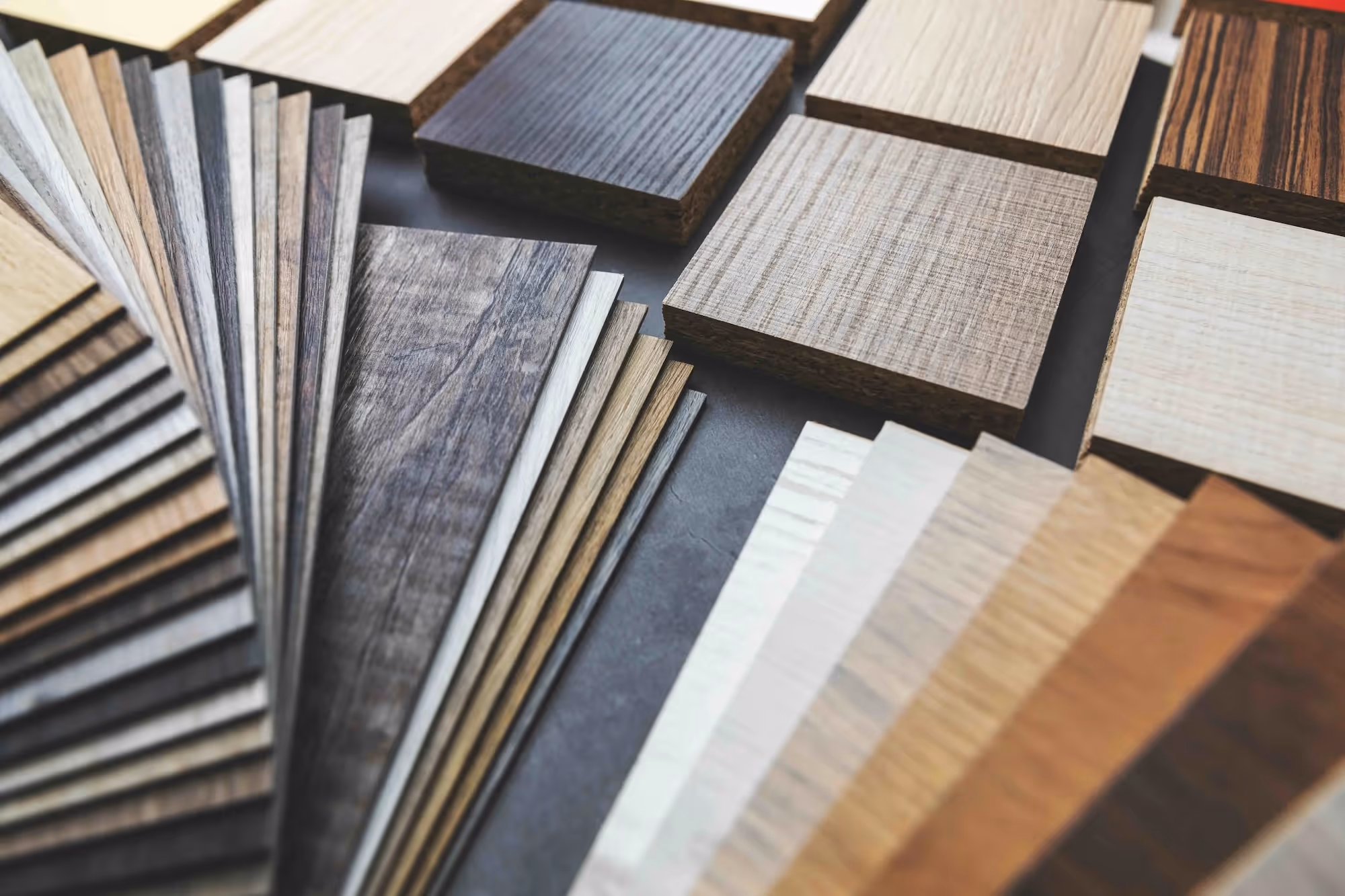 Variety of wood laminate samples arranged in fanned and square shapes, showcasing different colors and grain patterns.