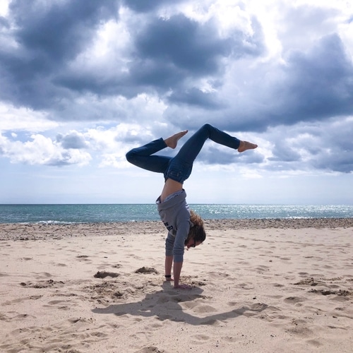 Anna is balancing in a handstand on a beautiful Irish beach