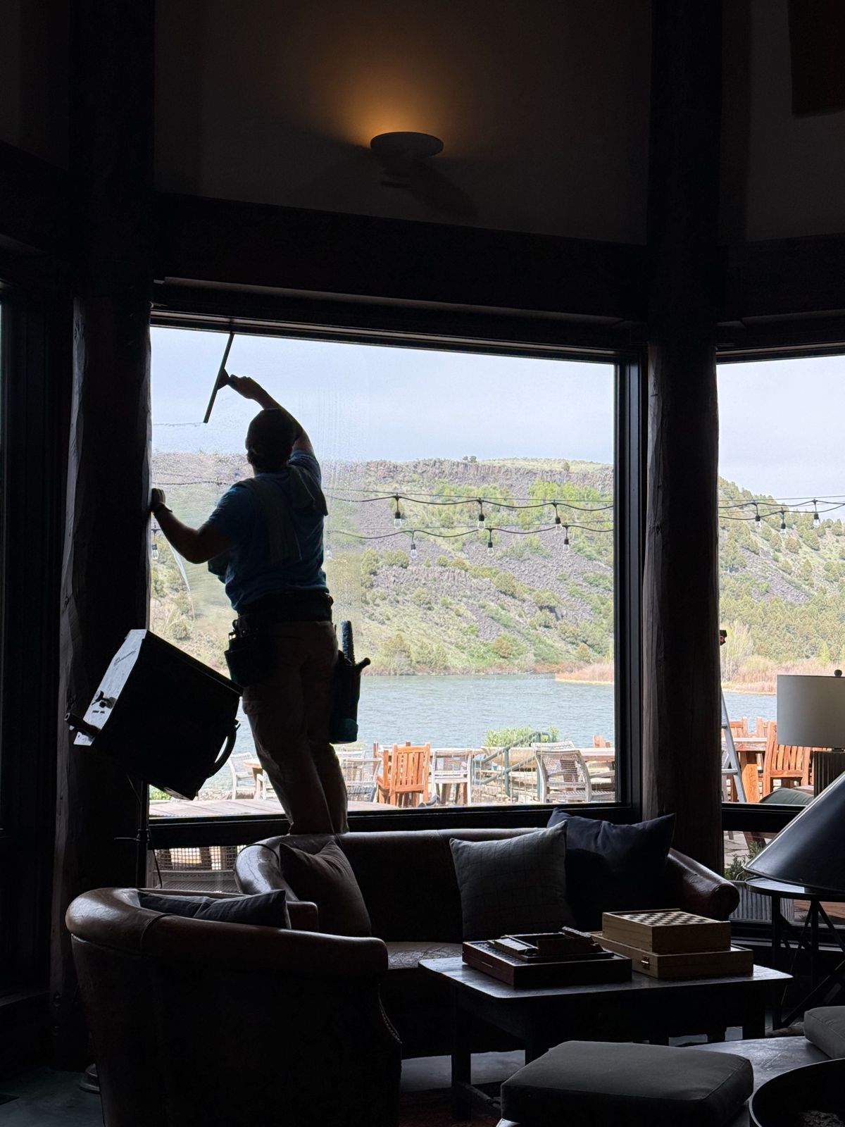 Window cleaner squeegeeing a large window overlooking a river canyon in Jackson Hole